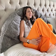 a woman laying on top of a bed with orange pants