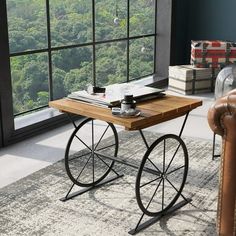 a wooden table sitting in front of a window next to a brown leather chair on top of a rug