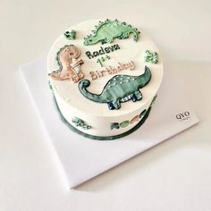 a birthday cake decorated with dinosaurs on top of a white tablecloth and napkin