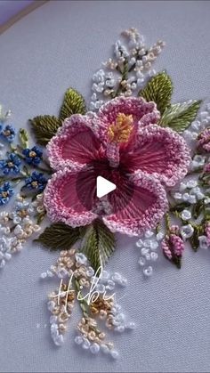 a close up of a flower on a piece of cloth with beads and flowers in the middle