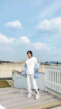 a man standing on top of a wooden deck next to a white fence and blue sky