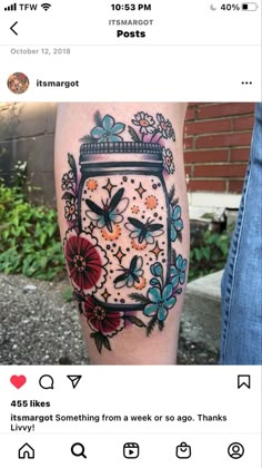 a person with a tattoo on their leg that has flowers and butterflies in a jar