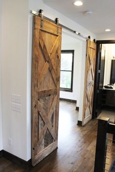 an open barn door in the middle of a living room with hardwood floors and white walls