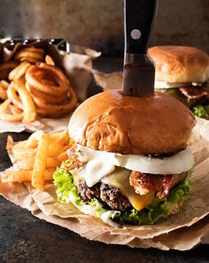 a knife sticking out of the top of a burger with french fries on the side