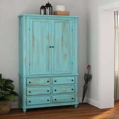 an old blue armoire in the corner of a room with a potted plant