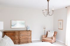 a bedroom with a chair, dresser and chandelier hanging from it's ceiling