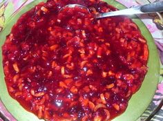 a green bowl filled with red sauce on top of a floral tablecloth covered table