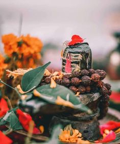 an arrangement of flowers and leaves on a table with a jar filled with chocolates