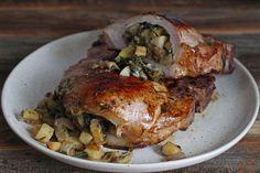 two pieces of meat sitting on top of a white plate next to potatoes and spinach