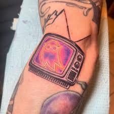 a person with a tattoo on their arm has a tv on his arm and is holding an apple