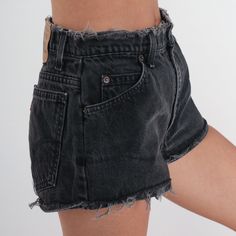 Vintage 90s denim shorts by Levis in black denim with a high rise waist and a raw cutoff edge. Please see measurements and condition below. Every garment we sell is authentic vintage! You will receive the exact item photographed. Condition: Very good vintage. Best fits women's: Labelled 9 to 10 Tag: levi's Material:  denim MEASUREMENTS Taken from seam to seam while the garment is lying flat. Double the armpit, waist, and hips For reference, model is 5'7" and measures 31-23-35. Waist: 14.5" Hips: 19.5" Inseam: 1" Rise: 11.5" For sales and promotions, follow us @Shopexile 90s Denim Shorts, High Rise Jean Shorts, Levis Denim Shorts, Jean Vintage, Black Levis, 90s Denim, Cut Offs, Denim Cutoffs, Levis Denim