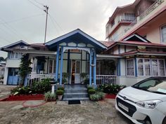 a white car parked in front of a blue and red house with two story windows