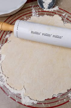 rolling dough on top of a red and white plate with a rolling pin next to it