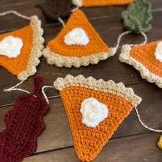 crocheted slices of pizza hanging from string on wooden table with other items nearby