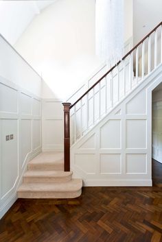 an empty staircase with wooden floors and white walls