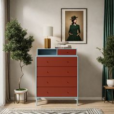 a room with a red dresser and a painting on the wall next to a potted plant