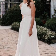 a woman in a white dress is standing on a brick walkway and smiling at the camera