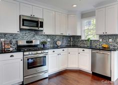 a kitchen with white cabinets and stainless steel stove top oven, dishwasher and microwave