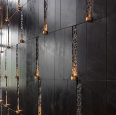 the wall is made up of black tiles with gold lights hanging from it's sides