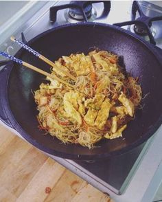 a wok filled with food sitting on top of a stove