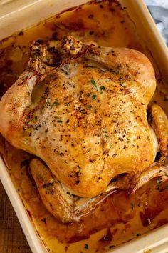 a roasted chicken in a casserole dish on a wooden table