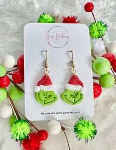 the grin face earrings are on display in front of some christmas decorations and pom poms