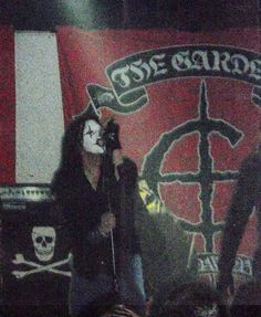 a man standing on top of a stage next to a microphone and skull head mask