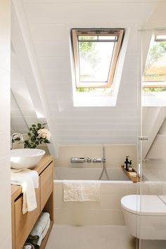 a white bathroom with a skylight above the bathtub and sink, is shown in this image