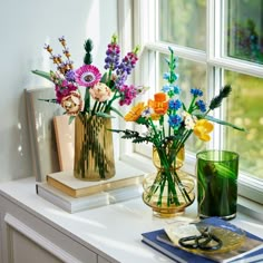 two vases filled with colorful flowers sitting on a window sill