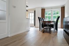 a dining room table and chairs in front of a flat screen tv on a wooden floor