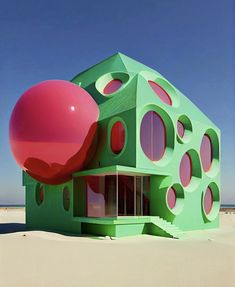 a green building with red circles on the front and side, in the middle of a sandy area