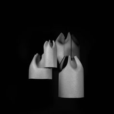 three white vases sitting next to each other on a black surface with one light turned on