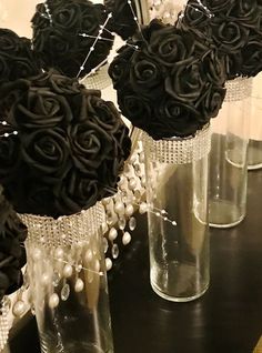 several vases with black roses and pearls are on a table in front of a mirror