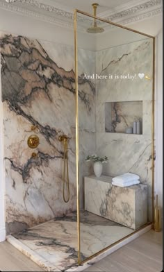 a bathroom with marble walls and flooring, gold fixtures on the shower head stand