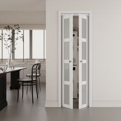 an open door leading to a kitchen and dining room with white walls, black counter tops and chairs