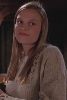 a woman sitting at a table in front of a wine glass and looking off into the distance