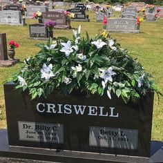 a cemetery with flowers and headstones in the grass