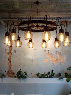 a chandelier hanging from the ceiling in a room with white couches and potted plants