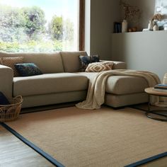 a living room with a couch, chair and rug on the floor in front of a window