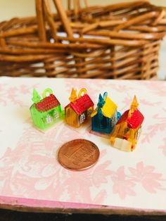 small toy houses sitting on top of a table next to a penny