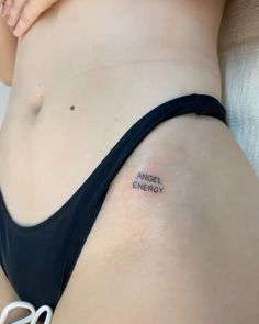 a woman's stomach with the words angel energy tattooed on her left side belly