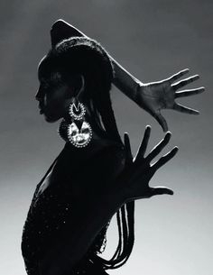 a black and white photo of a woman with her hands in the air, wearing large earrings