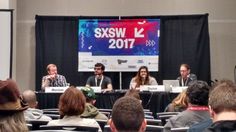 several people sitting at tables in front of a screen with the sxsw logo on it