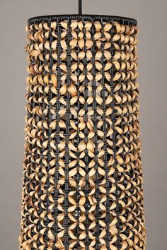 a lamp made out of woven material with black wire and wooden beads on the bottom