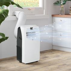 a white air conditioner sitting on top of a wooden floor next to a window