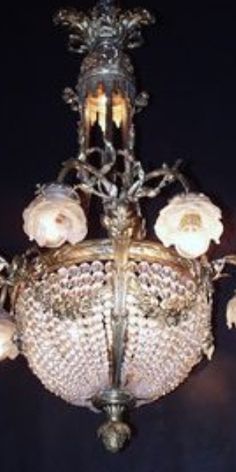 a chandelier with flowers on it hanging from the ceiling