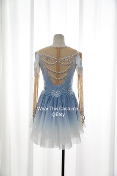 a blue and white dress with beading on the back, sitting on a mannequin