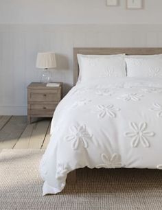 a bed with white sheets and pillows in a room