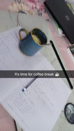 there is a notepad and coffee cup on the desk