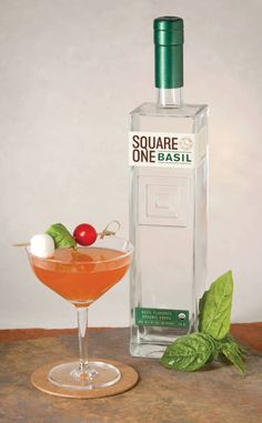 a bottle of alcohol next to a cocktail glass with a garnish in it